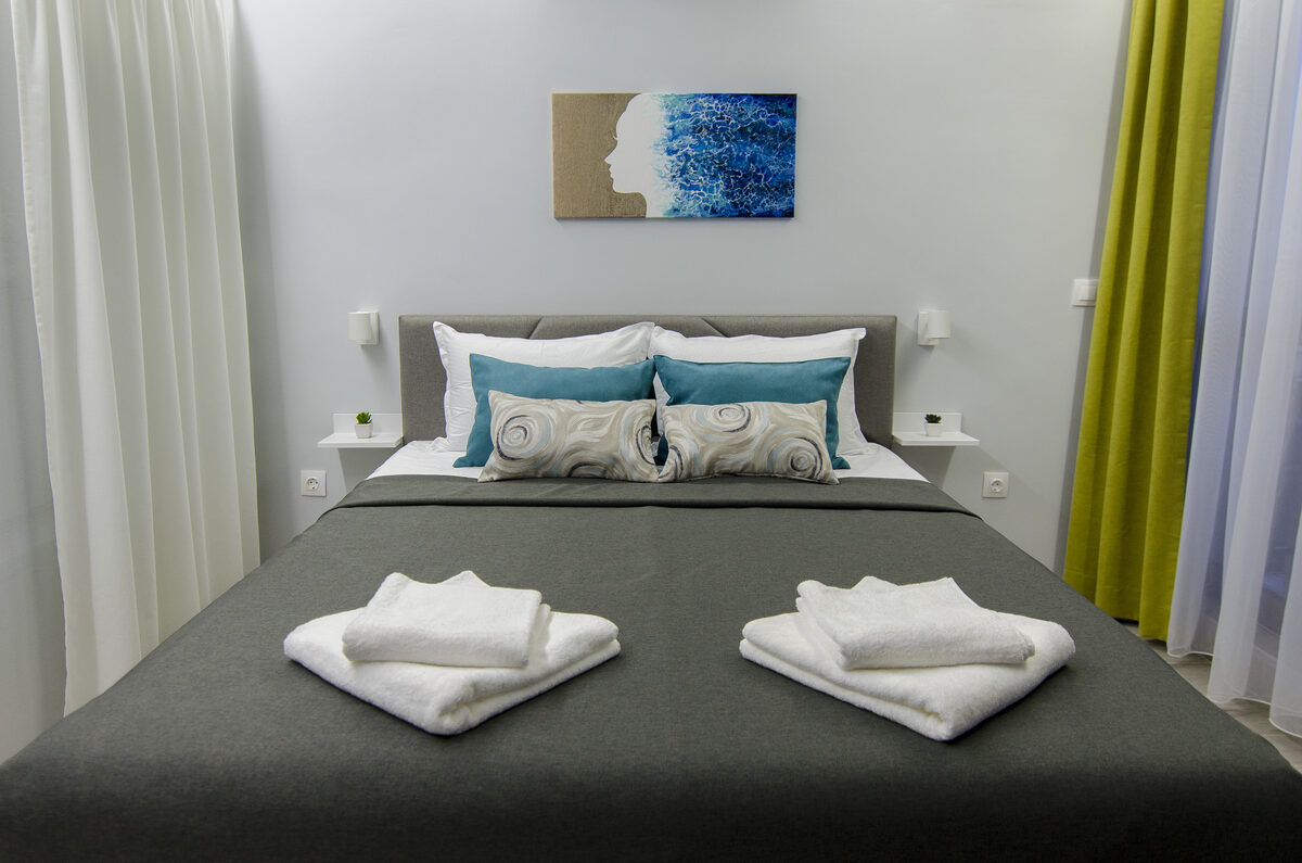 Bedroom with teal accent pillows, ocean artwork, and fresh white linens