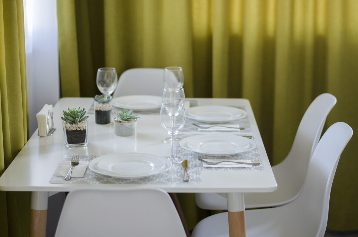 Complete dining table setup with four place settings and lime green curtain backdrop