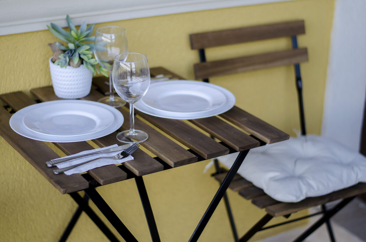 Balcony dining detail with white plates, wine glasses, and succulent decoration